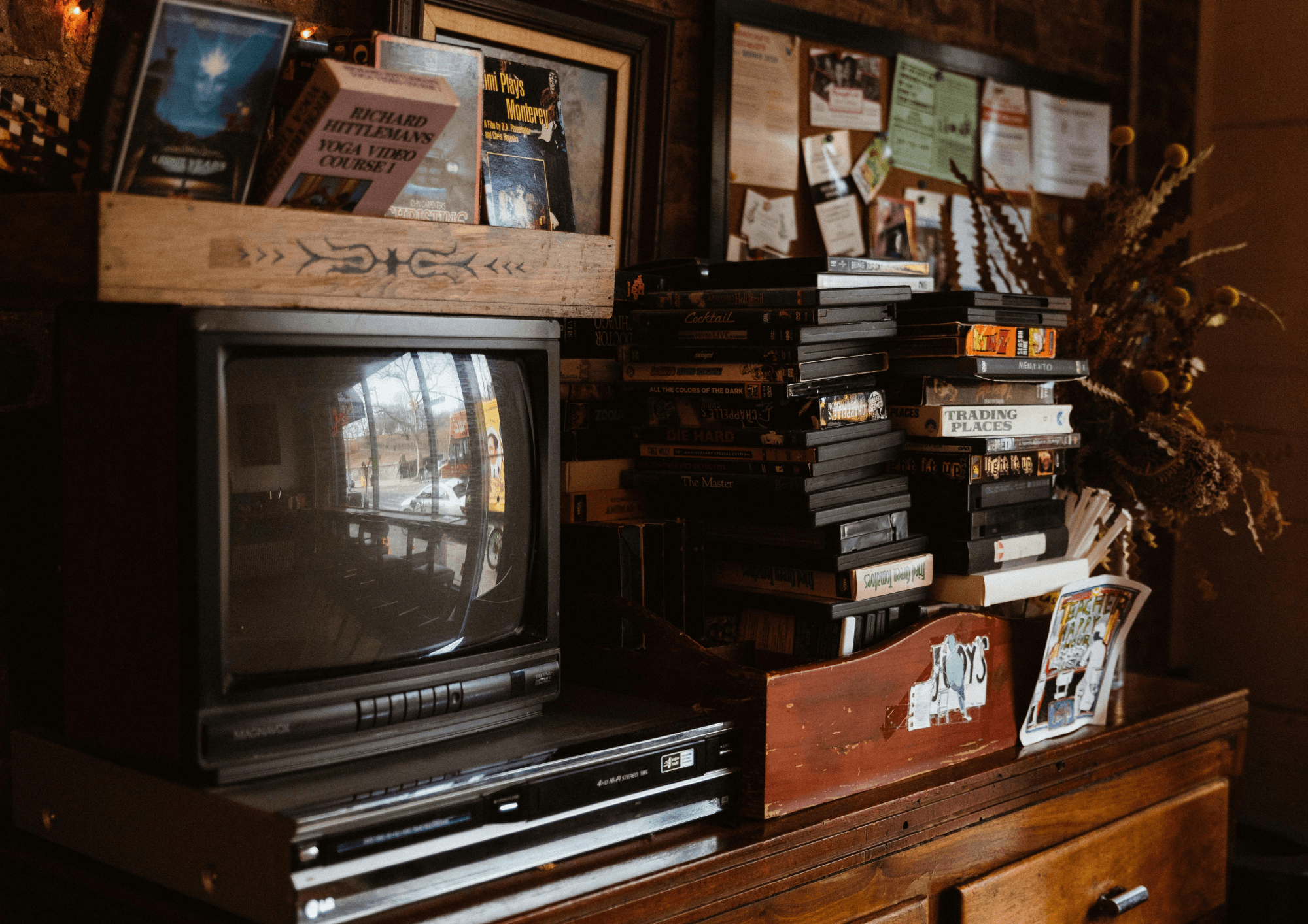 Stacks of VHS tapes and DVDs beside a CRT TV and VCR